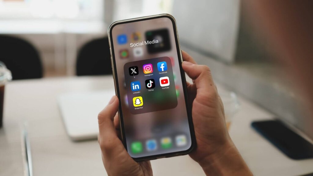 Social media platforms matter A close up shot of a mobile phone in hands with various social media apps on the screen.