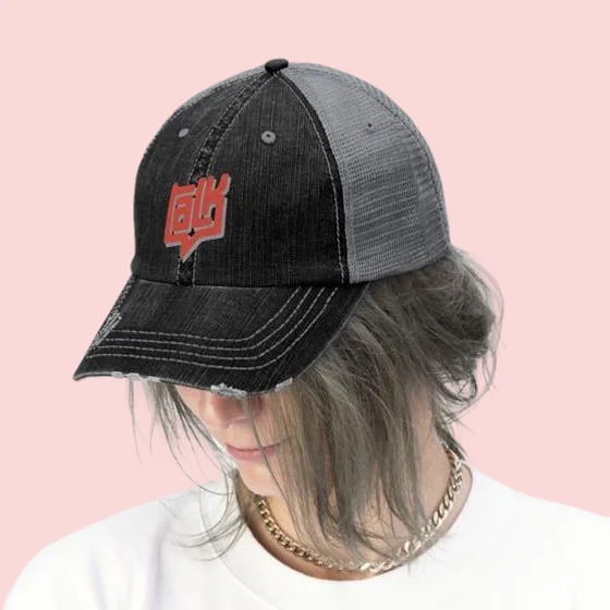 A person with gray streaked hair and a gold chain looking down. They are wearing a distressed black trucker hat with a gray mesh back which is embroidered with a red stylized graphic logo Custom clothing 44