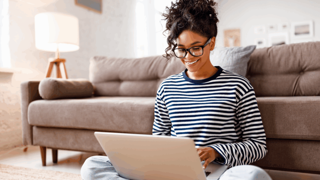 How can Etsy sellers use external trend reports for success A woman wearing glasses sits on the floor, focused on her laptop as she works or studies.